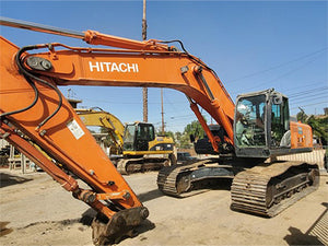 Orange Hitachi excavator on a construction site with clear blue sky.