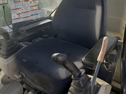 Close-up of a vehicle seat with controls and steering wheel inside Kobelco SK210 hydraulic excavator heavy machinery for sale near Corona CA at Westrax Machinery