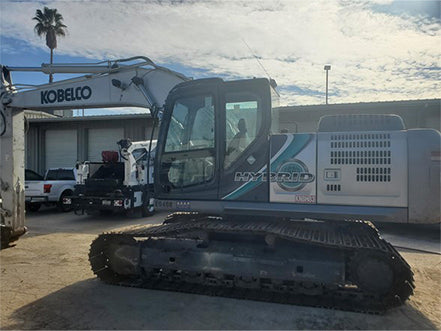Kobelco excavator in front of a building Kobelco SK210 hydraulic excavator heavy machinery for sale near Corona CA at Westrax Machinery